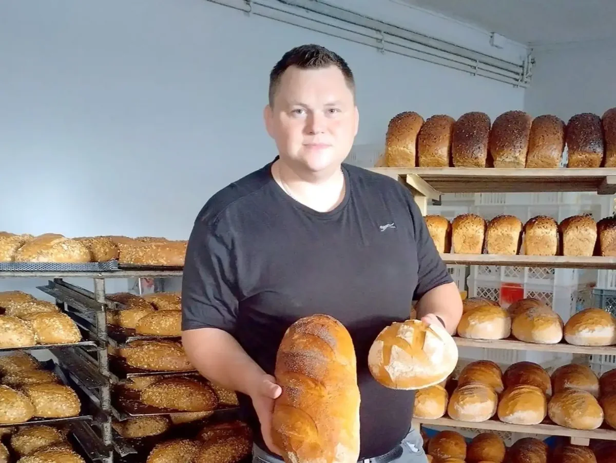Patryk Grabowski z bochenkami chleba w rodzinnej piekarni